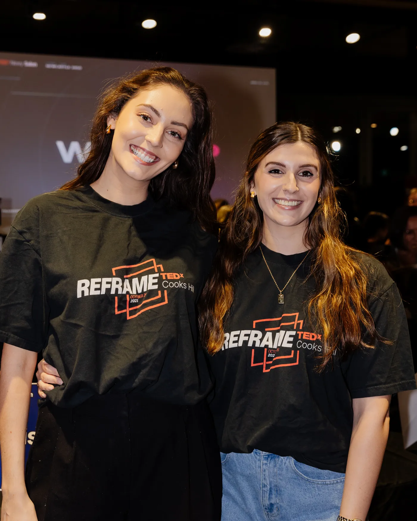 Two TEDxNewy volunteers smiling at Reframe, our 2025 flagship