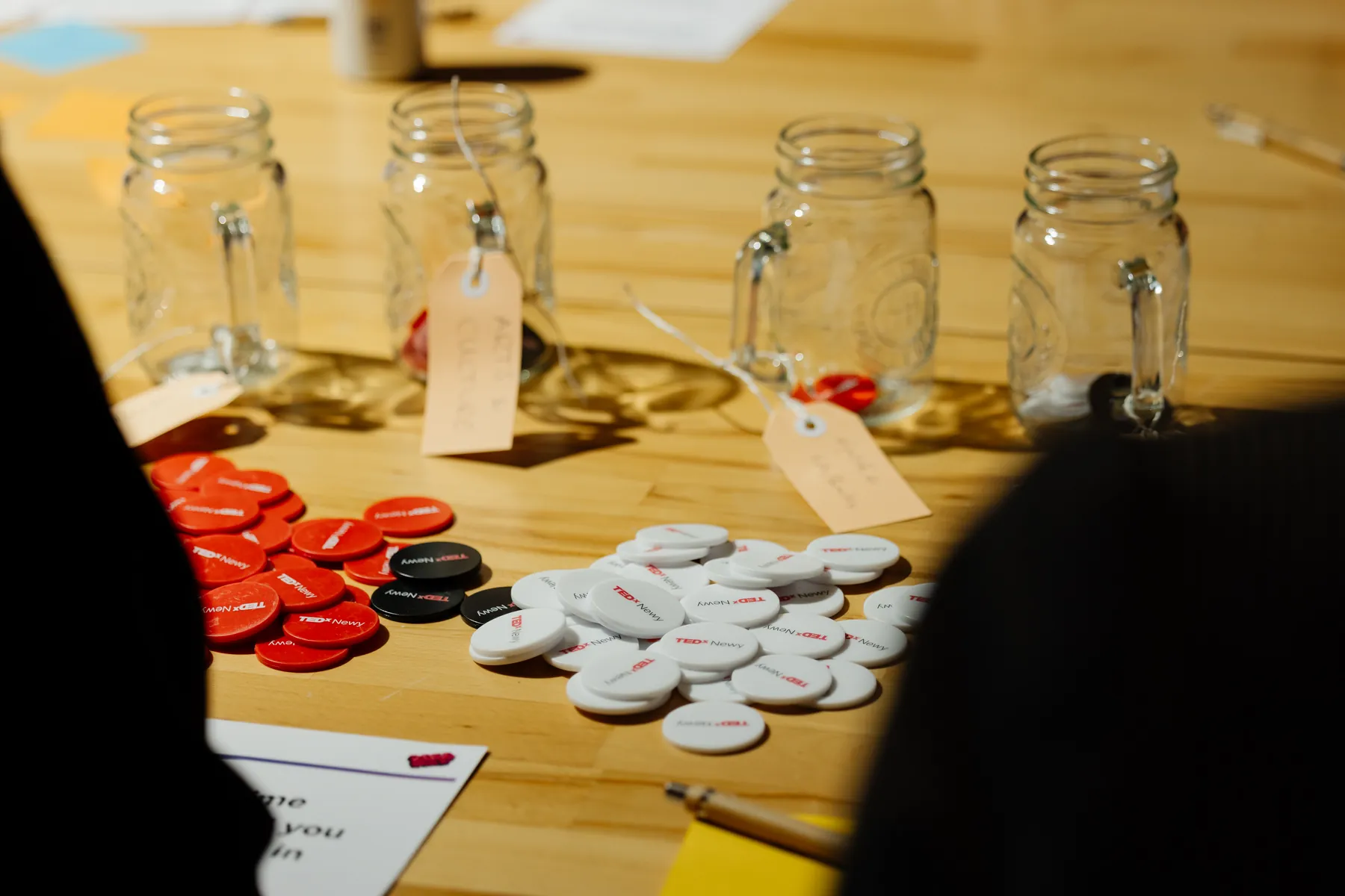 Piles of red, white and black voting tokens beside labelled glass jars.