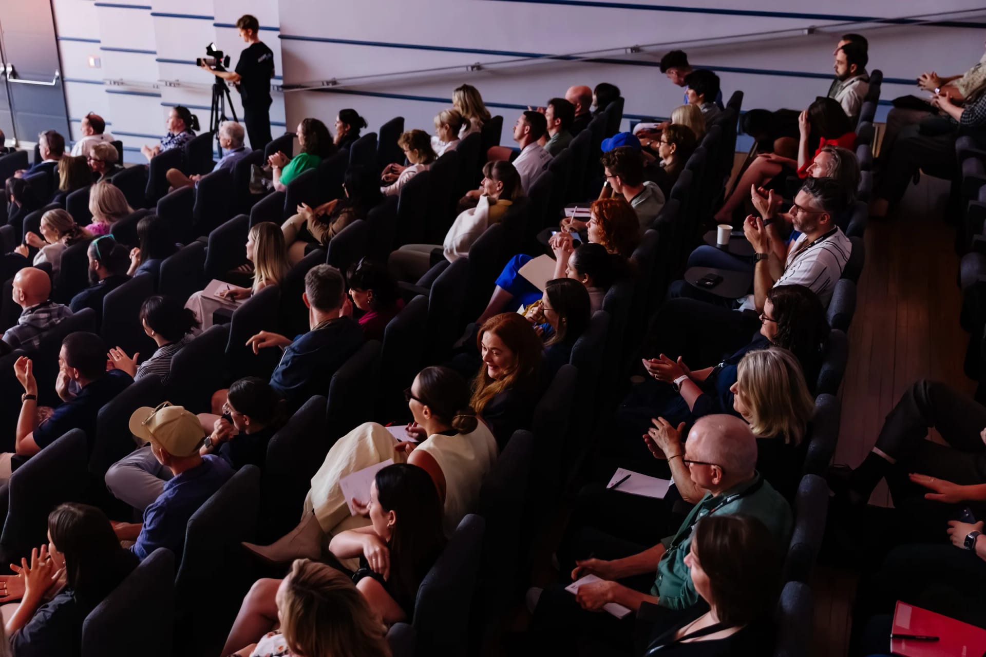 A full house of guests watching a talk at a TEDxNewy event.